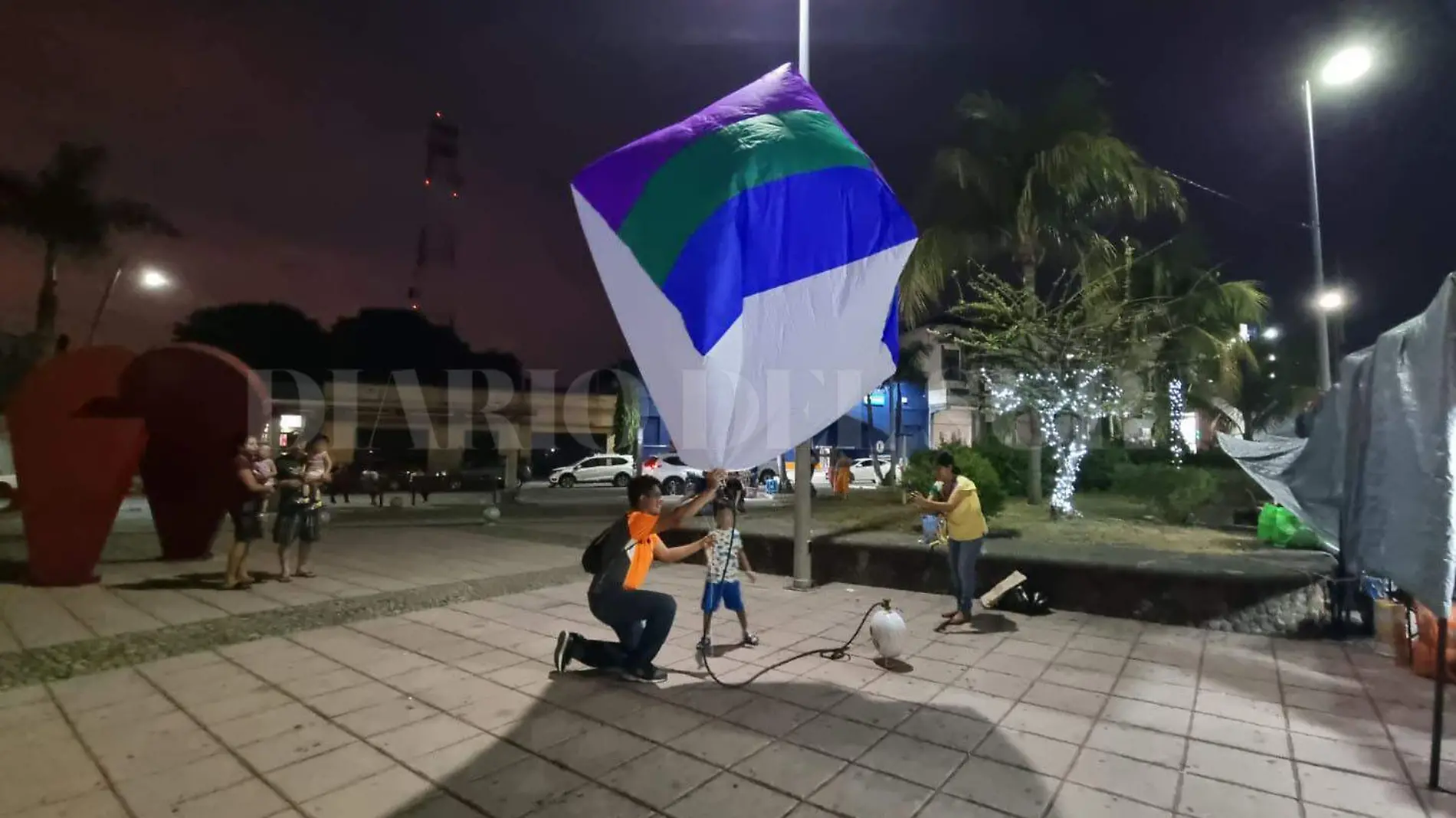 Niño y joven juegan con globo de cantoya